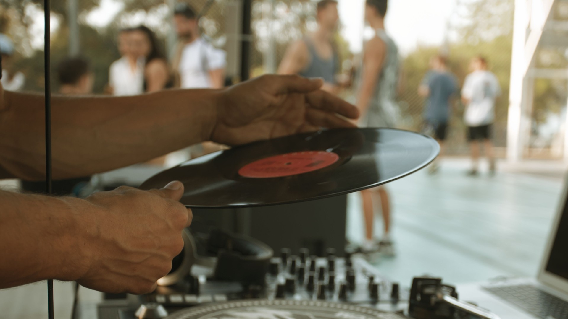 Male hands close-up holding vinyl record. Festival goers on the blurred background